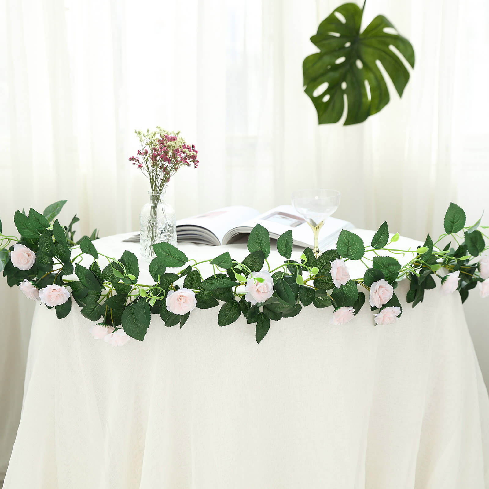 Blush artificial silk roses flower garland vine on a table.