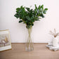Green artificial lemon leaf branches in a clear vase.