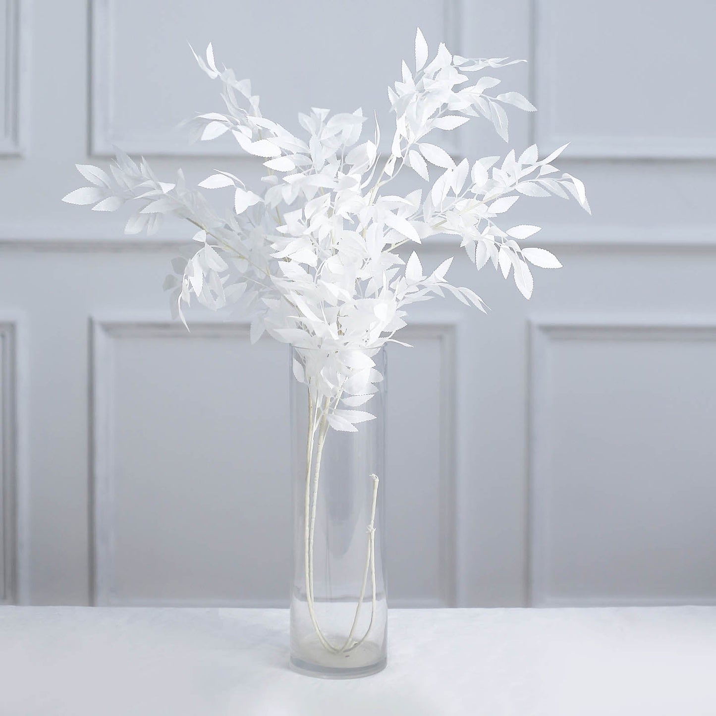 White artificial silk beech leaf branches in a clear vase.