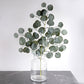 Frosted green artificial silk eucalyptus leaf stems in a glass vase.