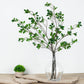 Green artificial ficus branches in a clear vase.