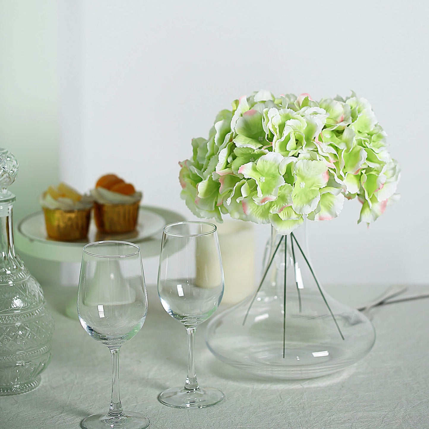 Lime and pink artificial satin hydrangeas in a glass vase.