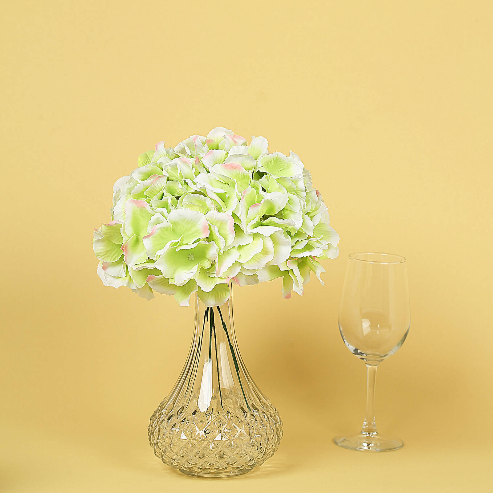 Lime and pink artificial satin hydrangeas in a clear vase.