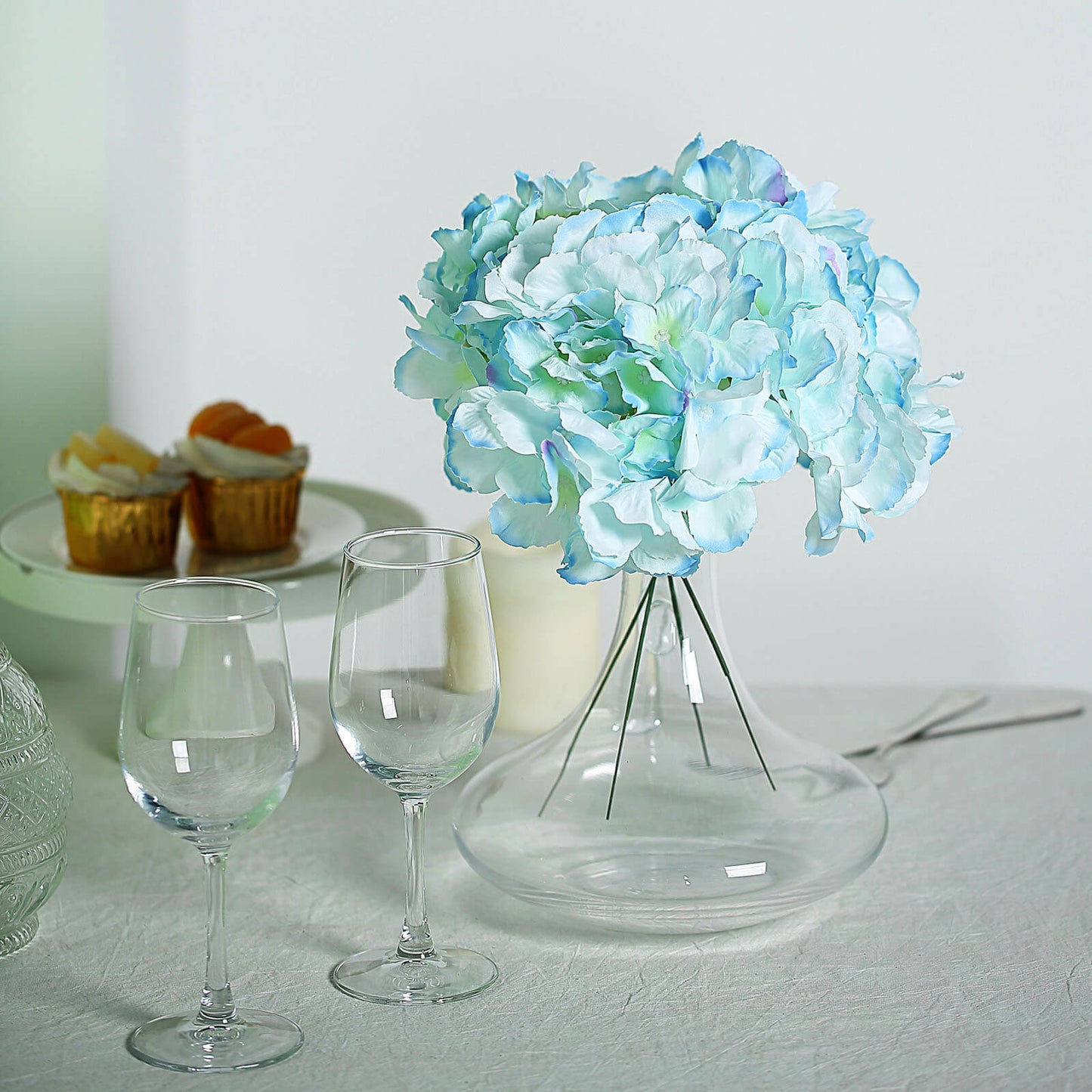 Blue artificial satin hydrangeas bouquet in a clear vase.