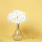 Cream artificial satin hydrangeas in a glass vase on a yellow background.