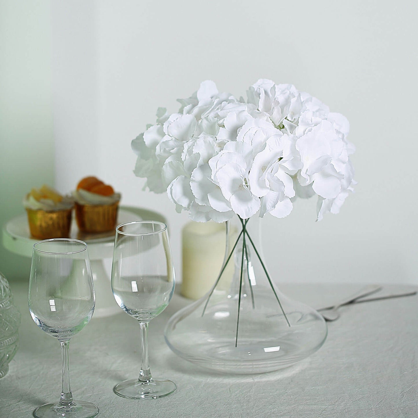 White artificial satin hydrangeas bouquet in a glass vase.