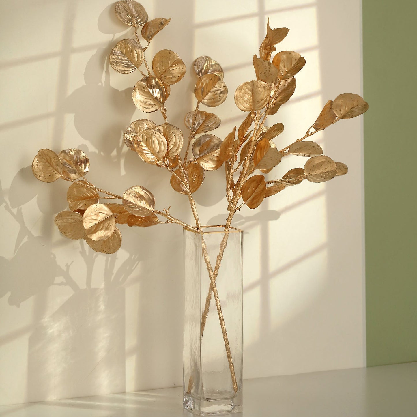 27" Metallic Gold Eucalyptus Leaf Branches in a clear vase.