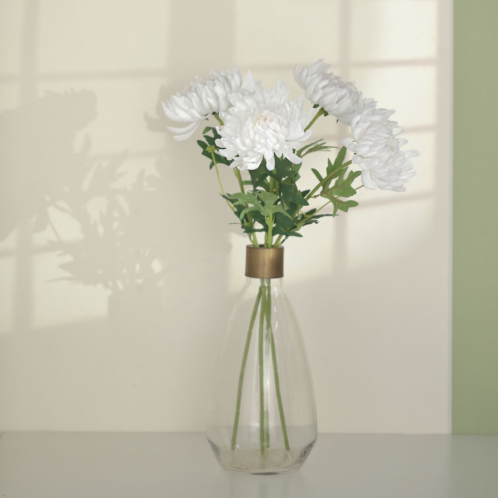 White artificial silk chrysanthemum bouquet in a clear vase.