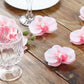 Pink artificial silk orchids for DIY crafts on a wooden surface.