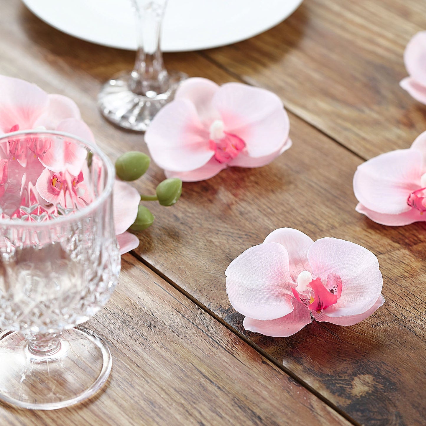 Pink artificial silk orchids for DIY crafts on a wooden surface.