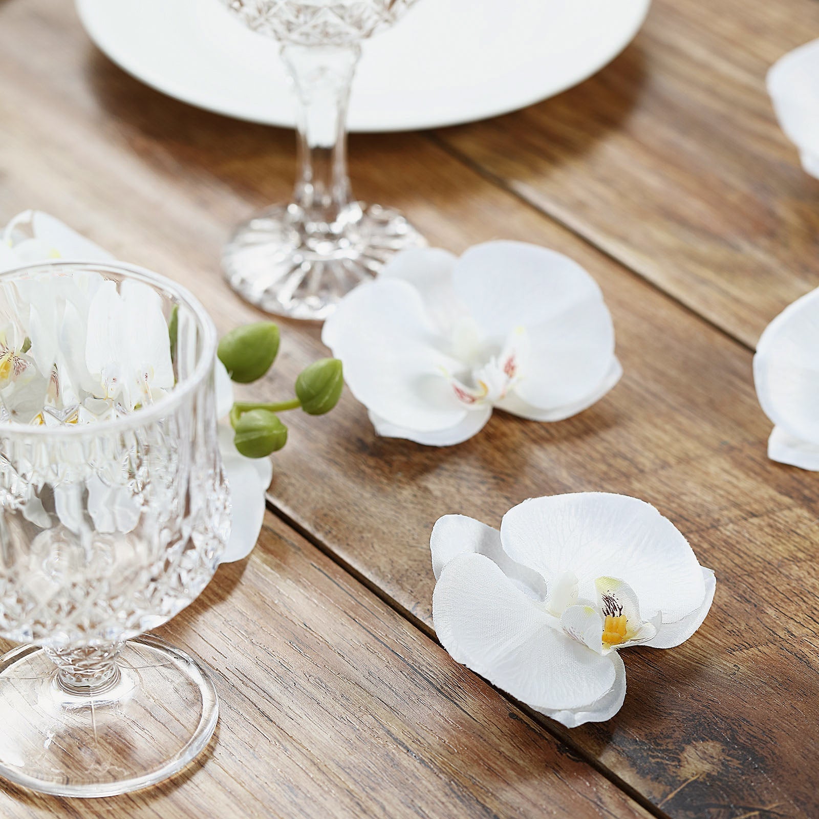 White artificial silk orchids for DIY crafts on a wooden table.