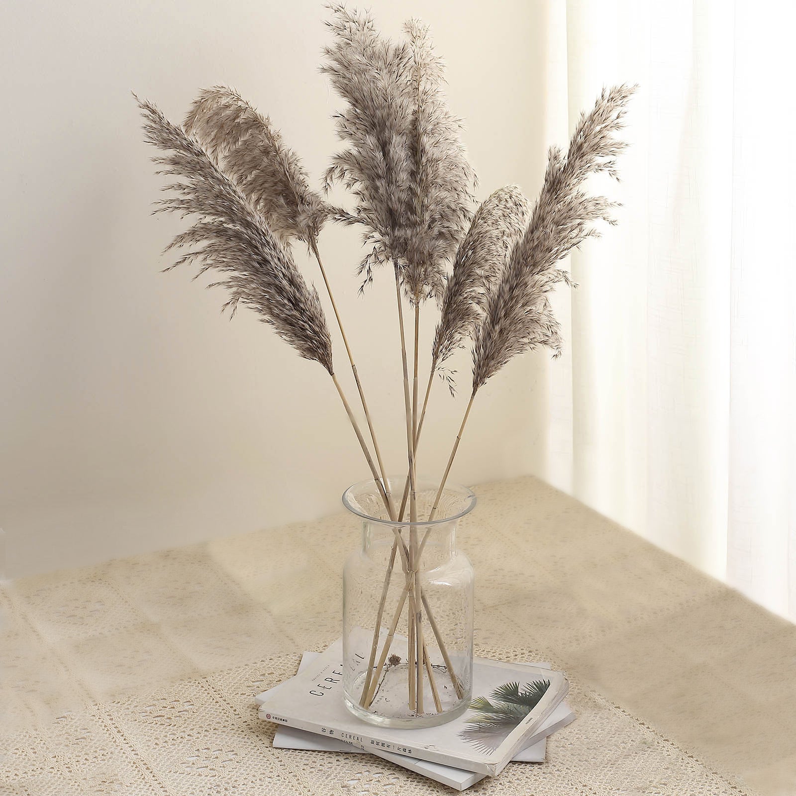 Natural tint dried pampas grass in a clear vase on a table.