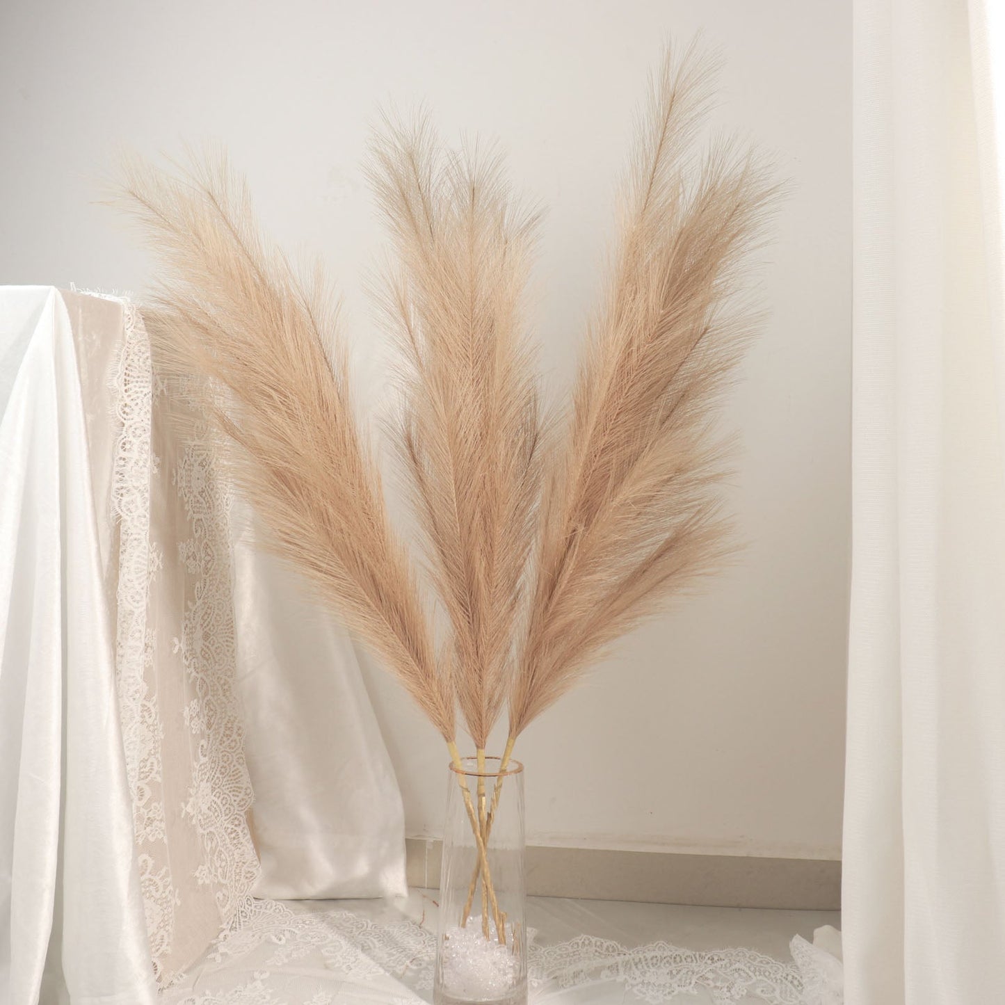 Taupe artificial pampas grass sprays in a clear vase.