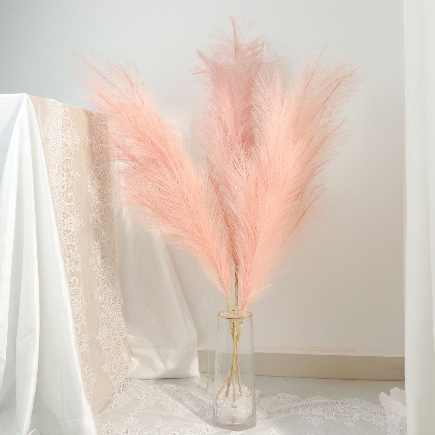 Dusty rose artificial pampas grass arrangement in a glass vase.