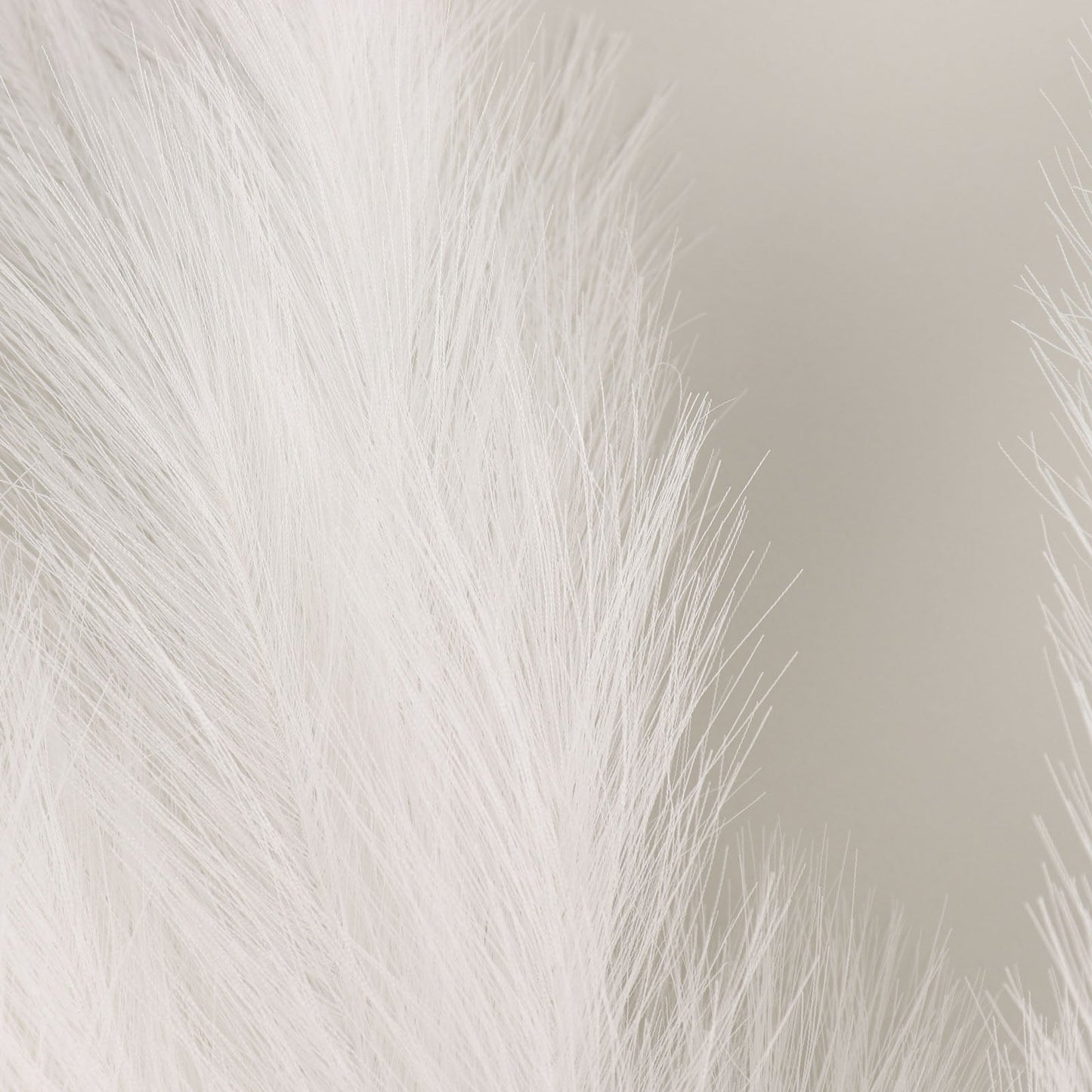 White artificial pampas grass plant sprays in a vase arrangement.