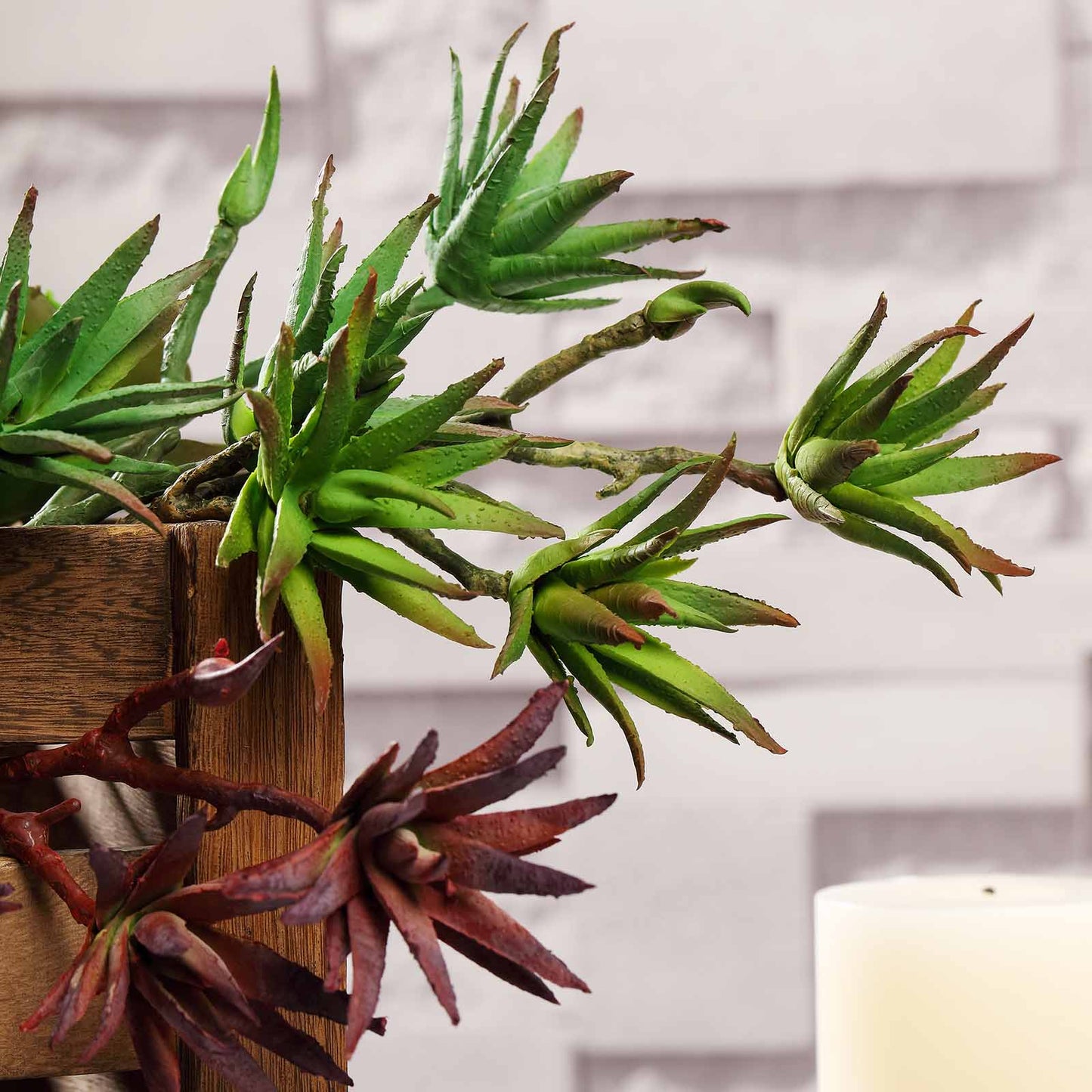 Assorted green artificial yucca and aloe vera succulent plants in a wooden planter.