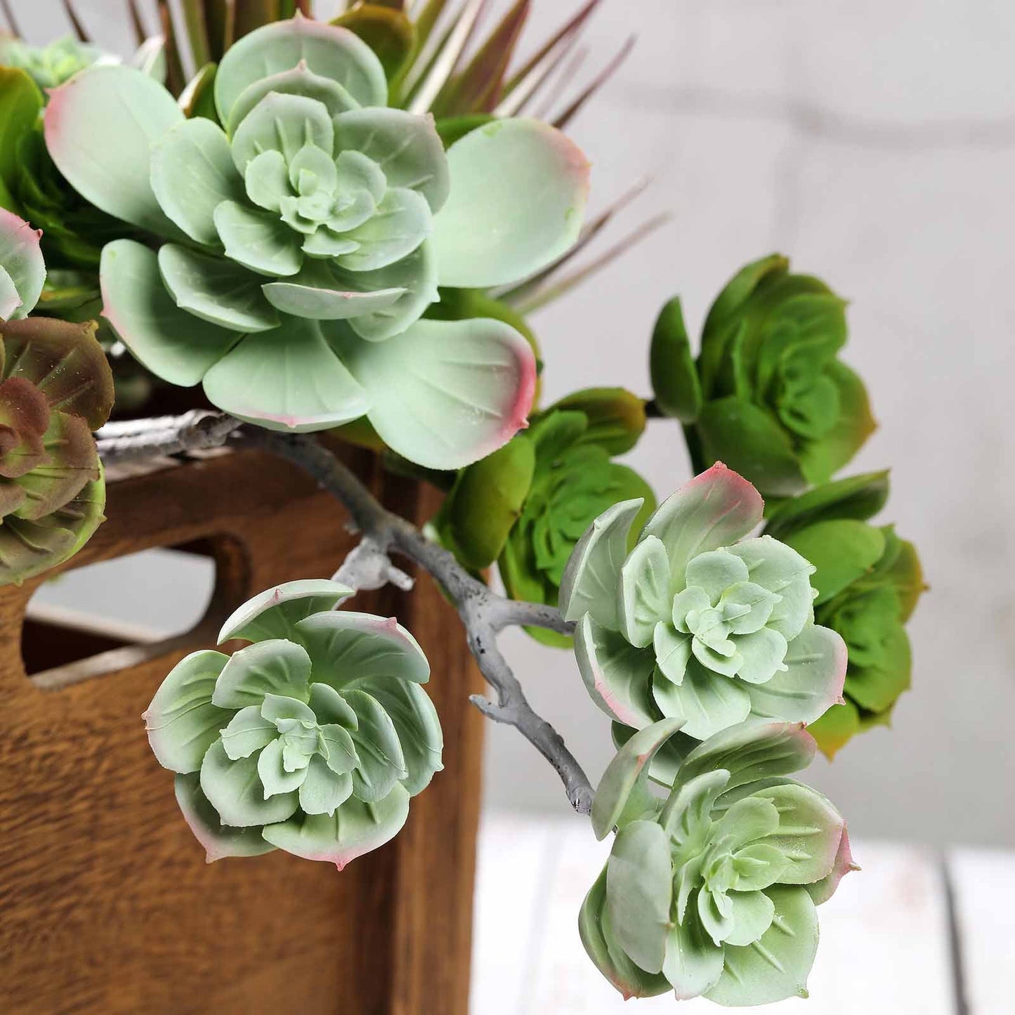 Assorted green artificial Echeveria succulent air plants in a wooden container.