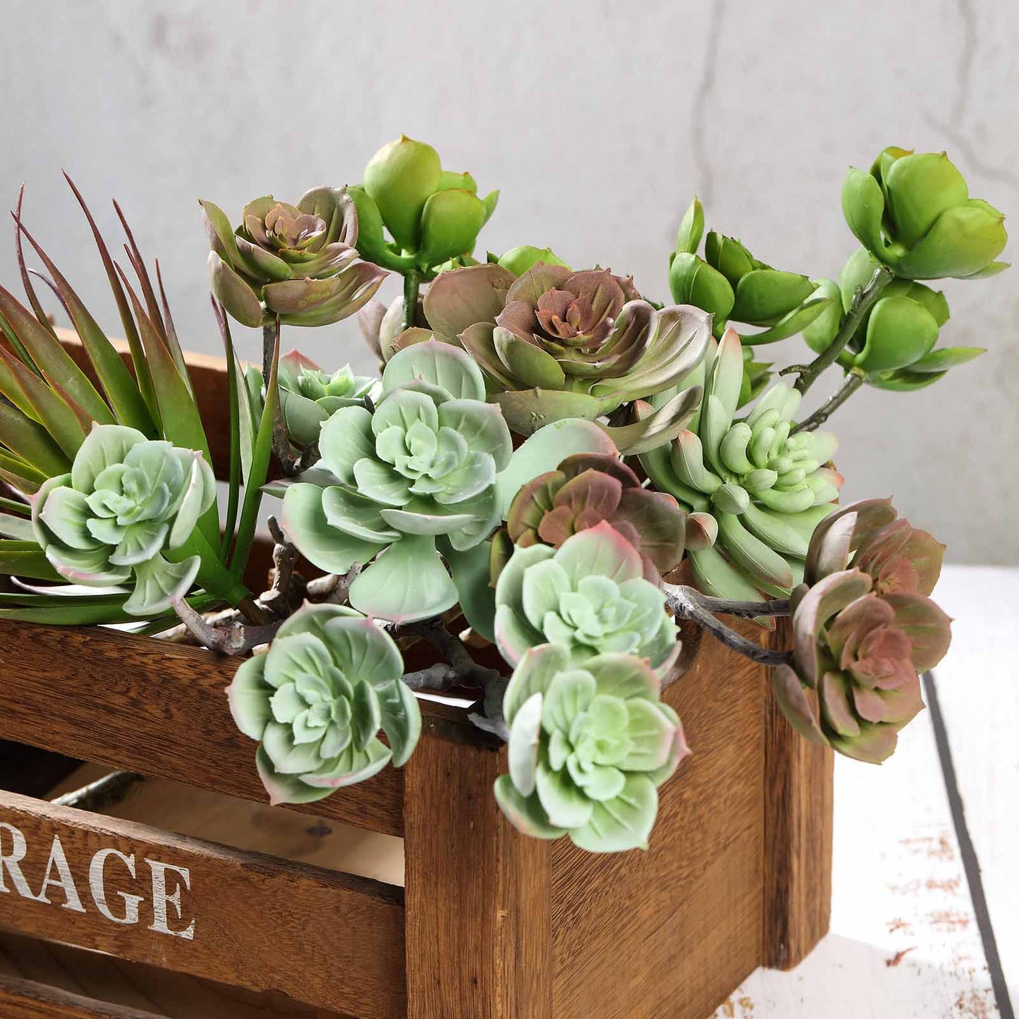 Assorted green artificial echeveria stem succulents in a wooden crate.