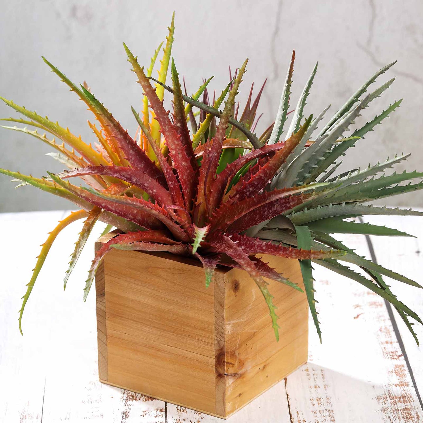 Colorful artificial aloe succulent plants in a wooden pot.
