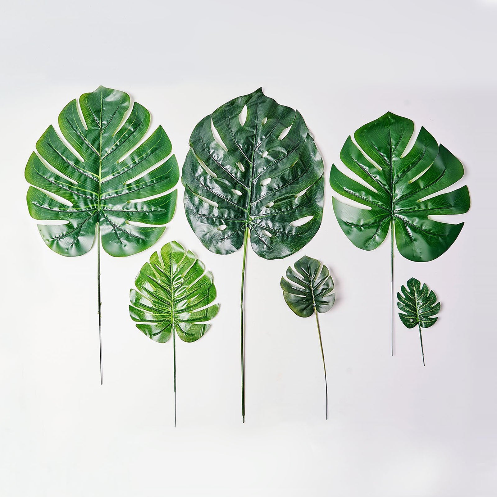 Assorted green artificial silk tropical monstera leaf plants.