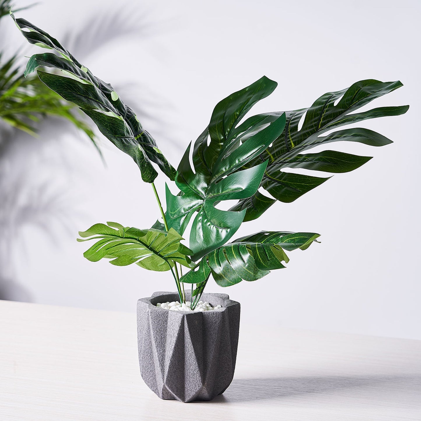 Assorted green artificial silk tropical monstera leaf plants in a gray pot.