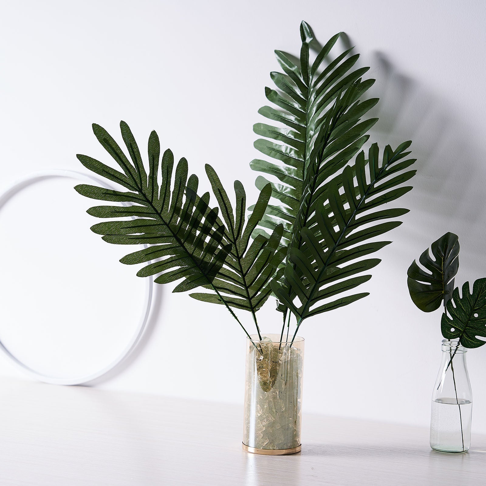 Assorted green artificial silk tropical palm leaf plants in a vase.