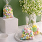 Clear gift bags filled with pastel candy treats and gold twist ties.