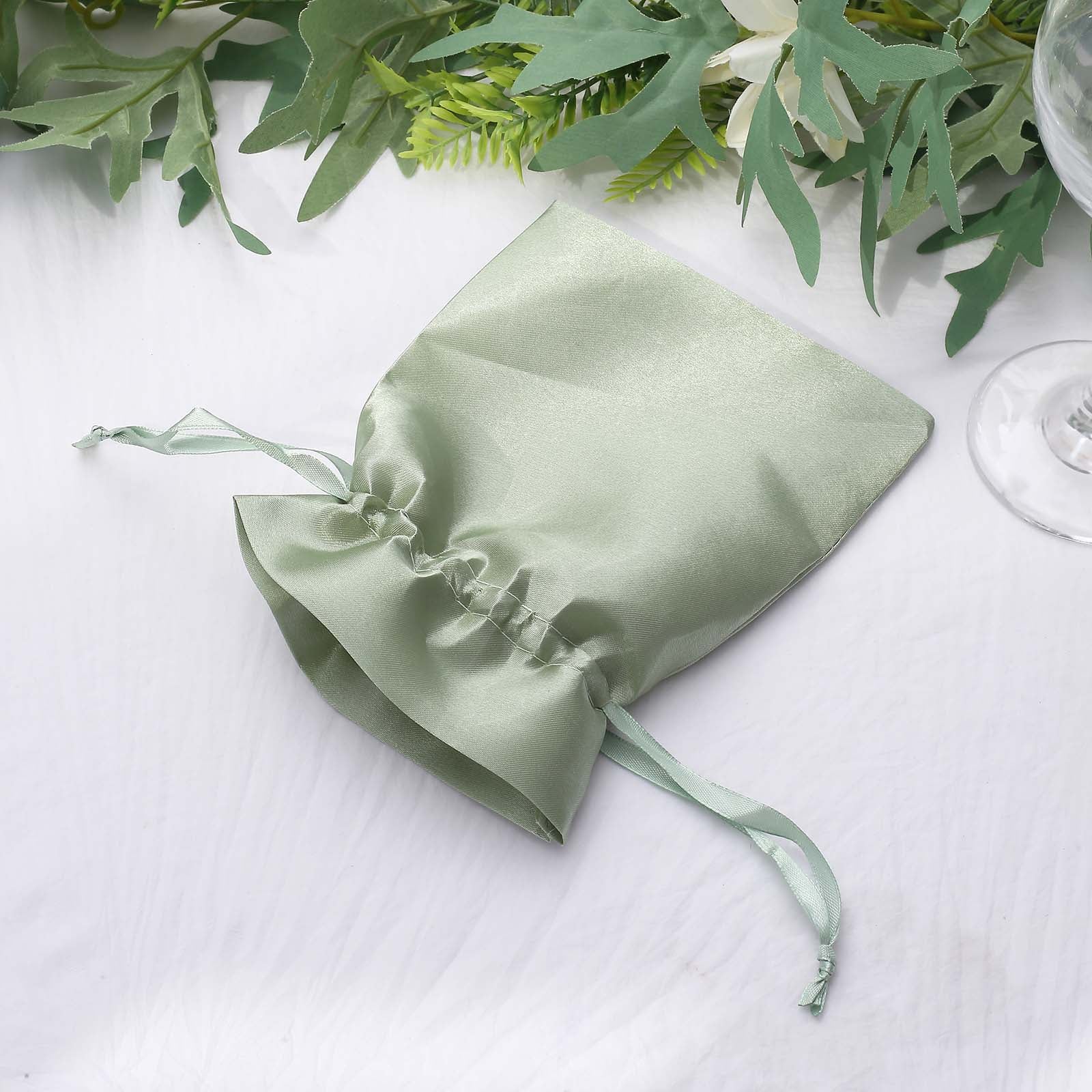 Sage green satin drawstring wedding favor gift bag on a white surface.