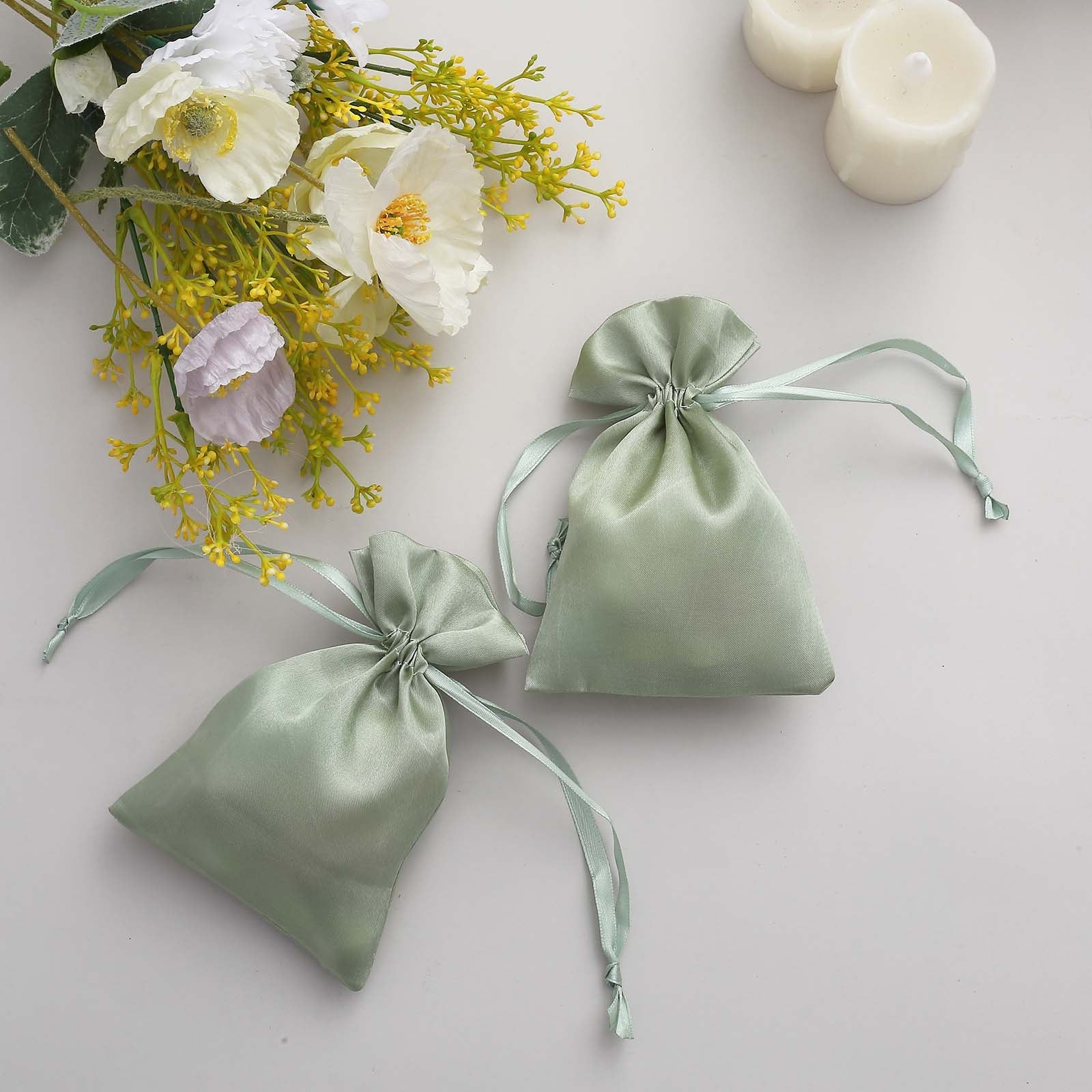 Sage green satin drawstring favor bags for weddings and parties.