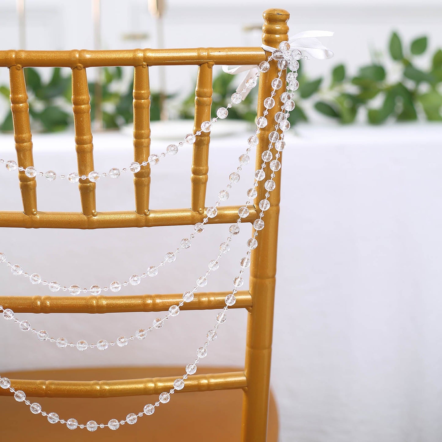 Clear faux pearl beaded chair back garland on a gold Chiavari chair.