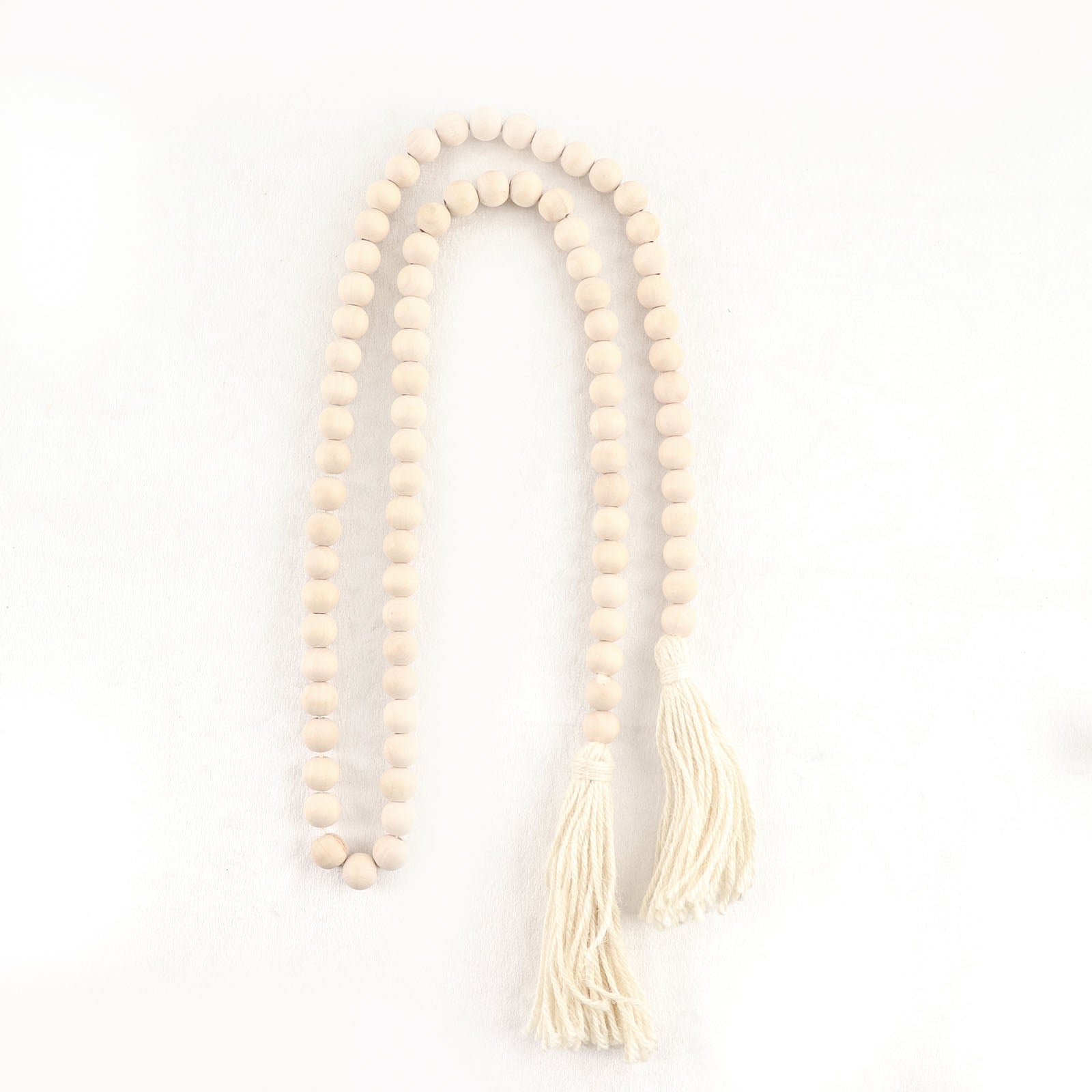 Cream wood bead garland with tassels for rustic boho decor.