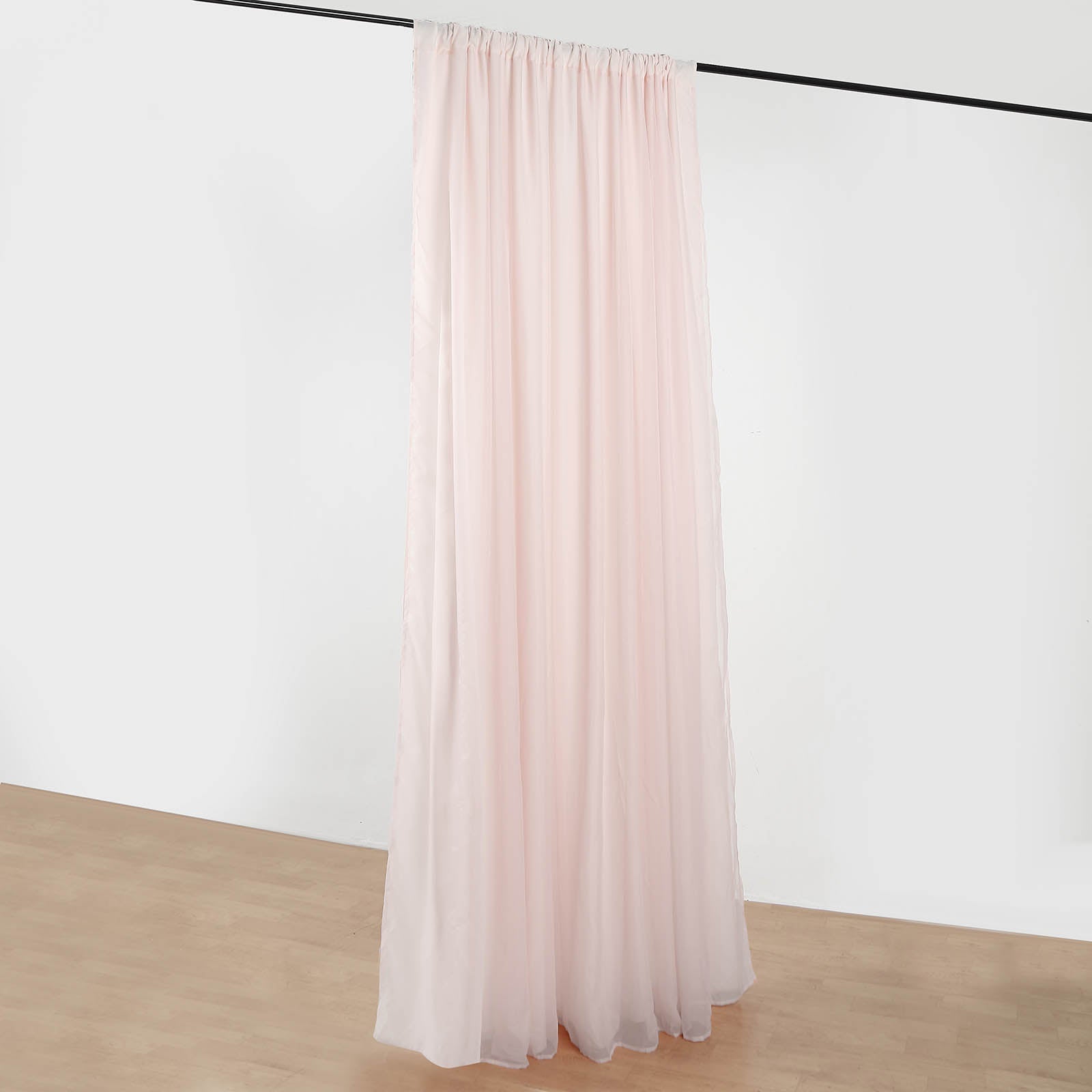 Blush chiffon polyester event curtain drapes hanging on a rod.