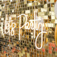 Ritzy gold sequin wall backdrop with neon "Let's Party" sign.
