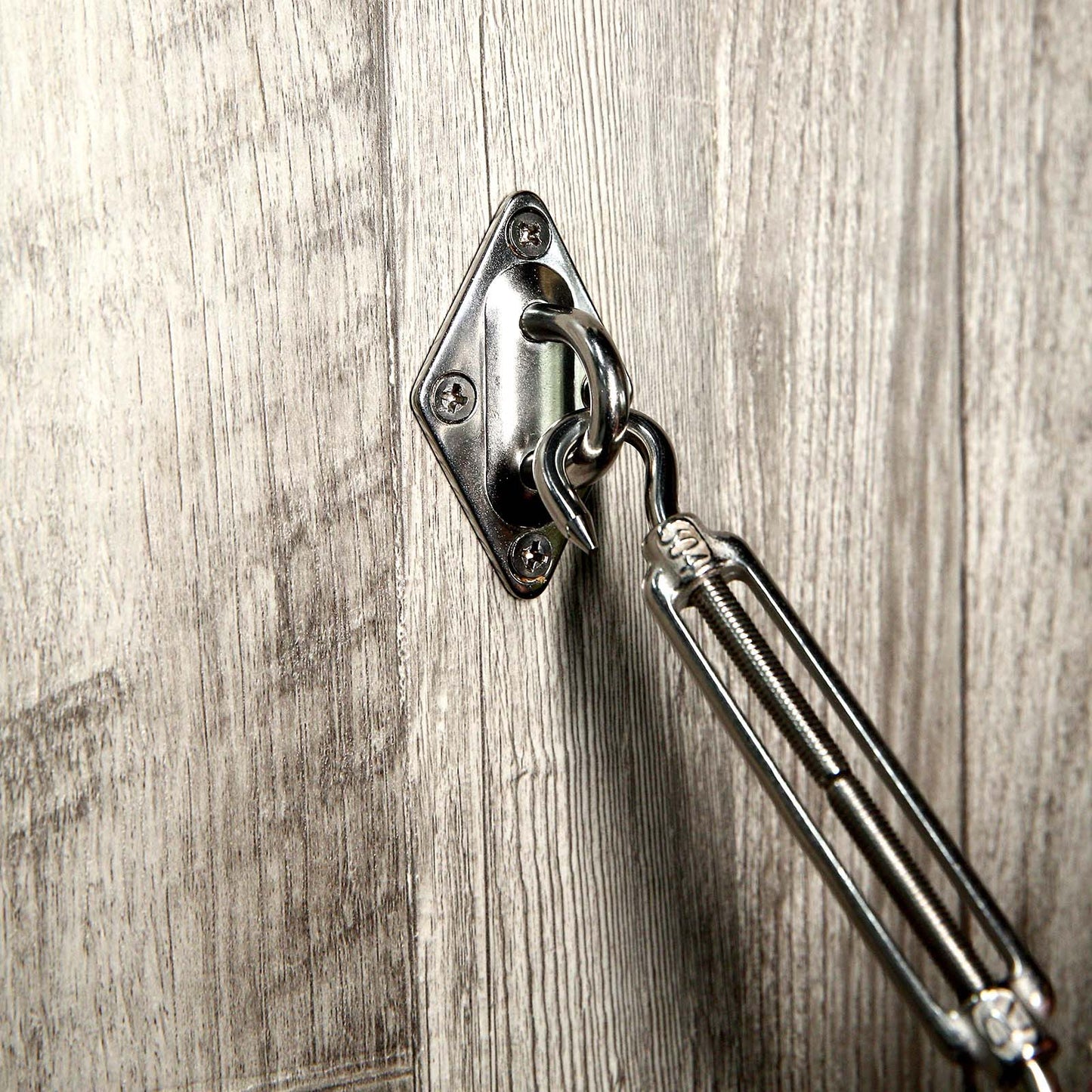 Stainless steel sun shade sail installation hardware kit on wood surface.