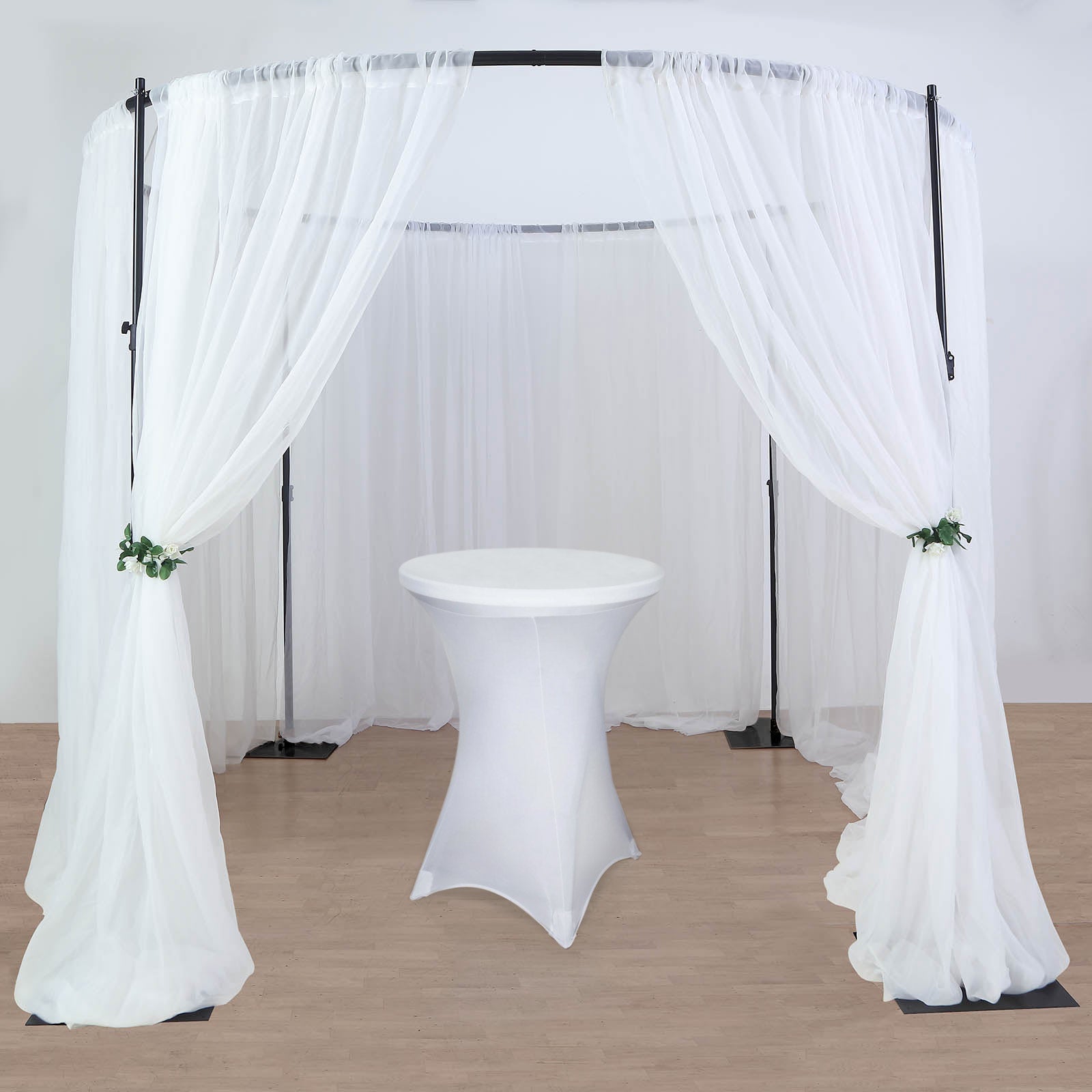 Black metal wedding arch with white drapes for events.
