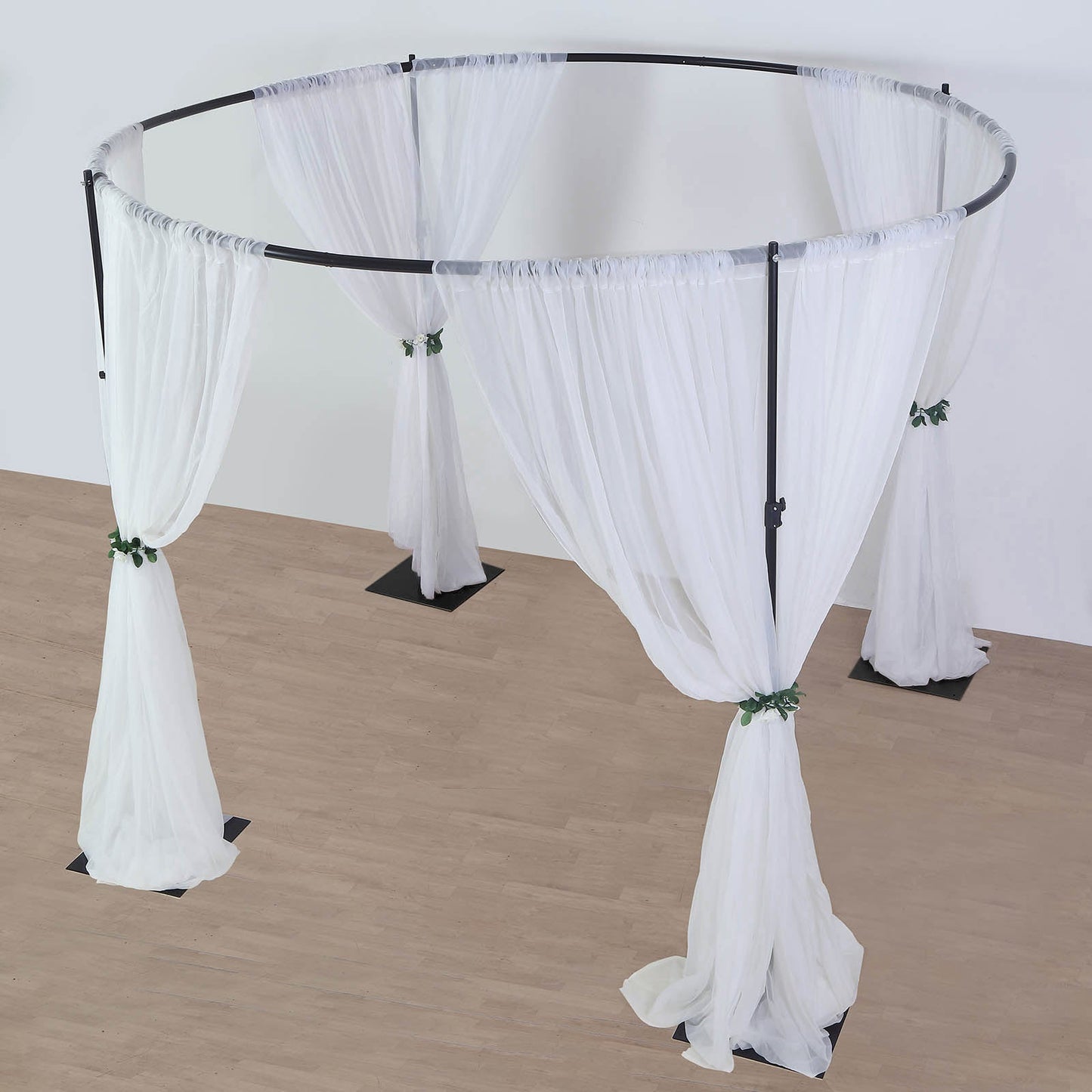 Black metal circular wedding arch stand with white drapes.