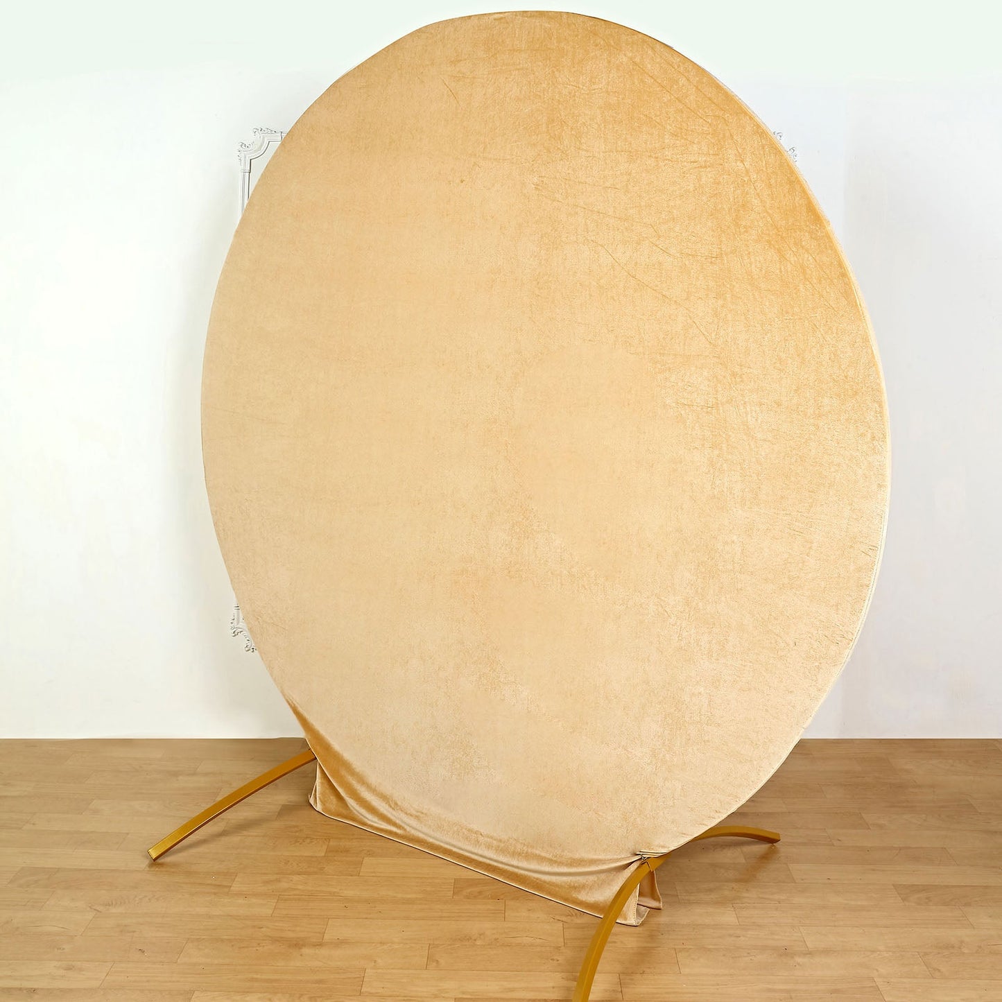 Champagne soft velvet round wedding arch cover on a wooden floor.