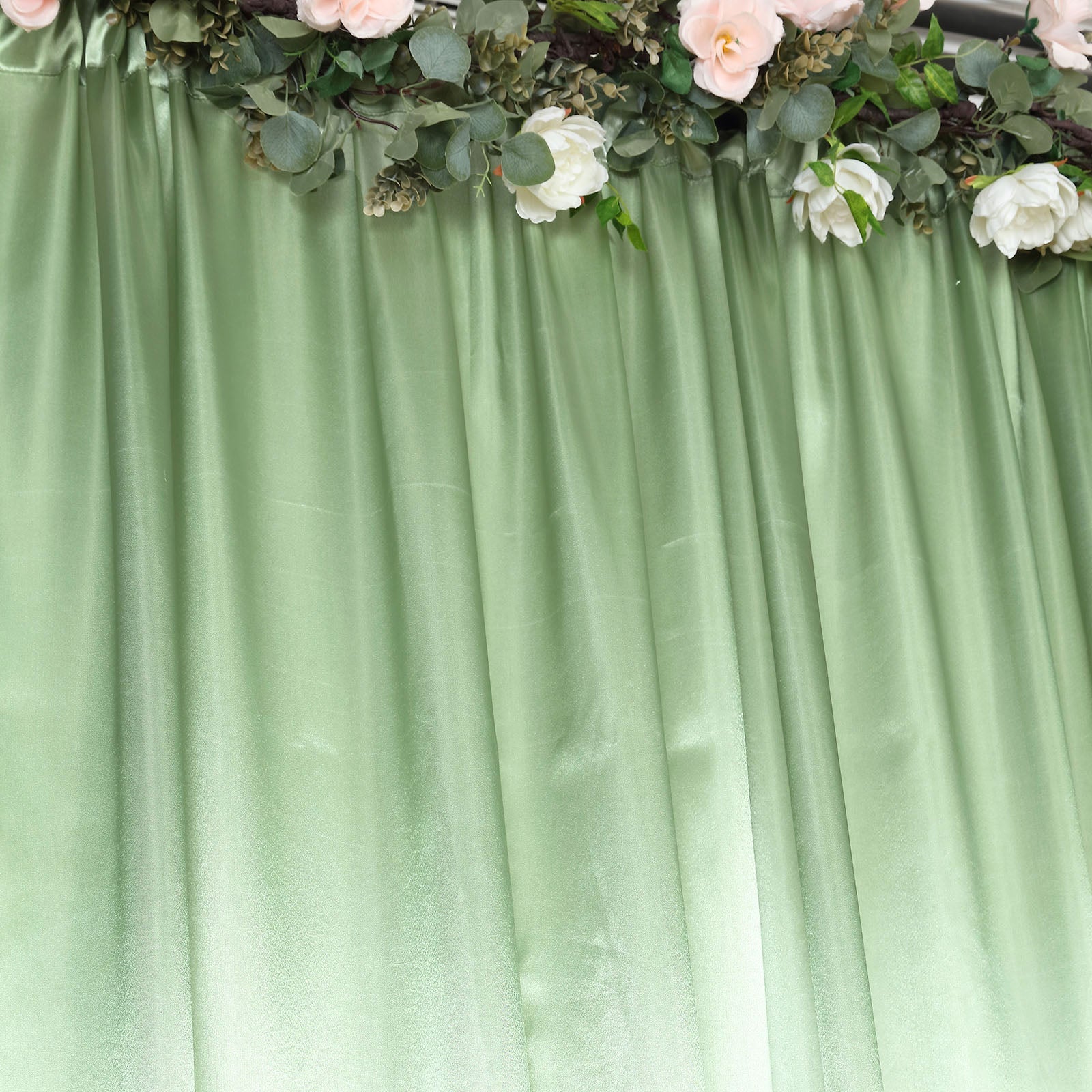 Sage green satin event curtain drapes with floral accents.