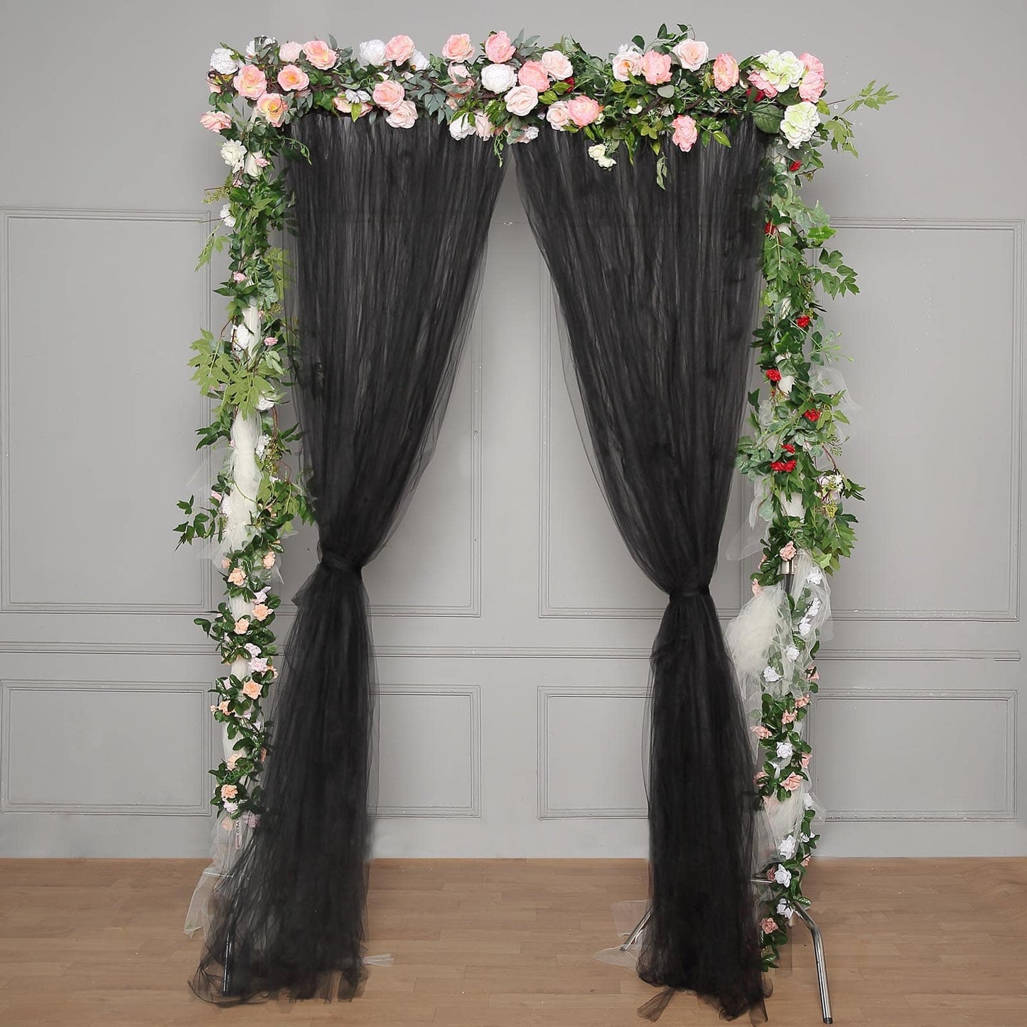 Black sheer tulle event curtain drapes with floral decoration.