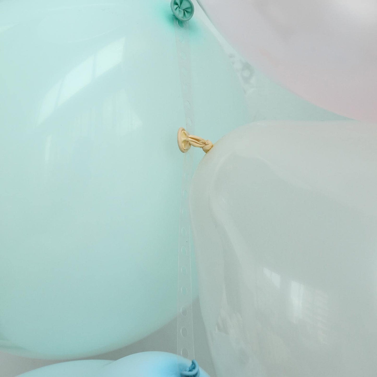 Mint green balloon arch kit with decorating strips and balloon tie tool.