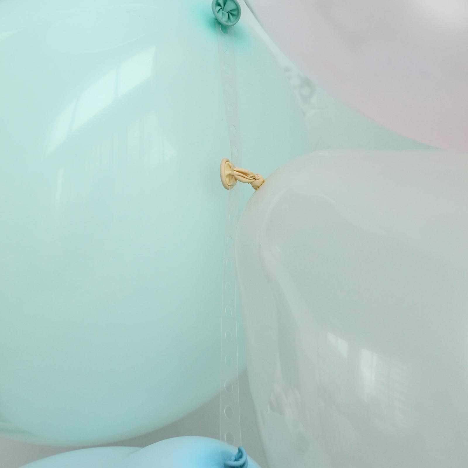 Mint green balloon arch kit with decorating strips and balloon tie tool.