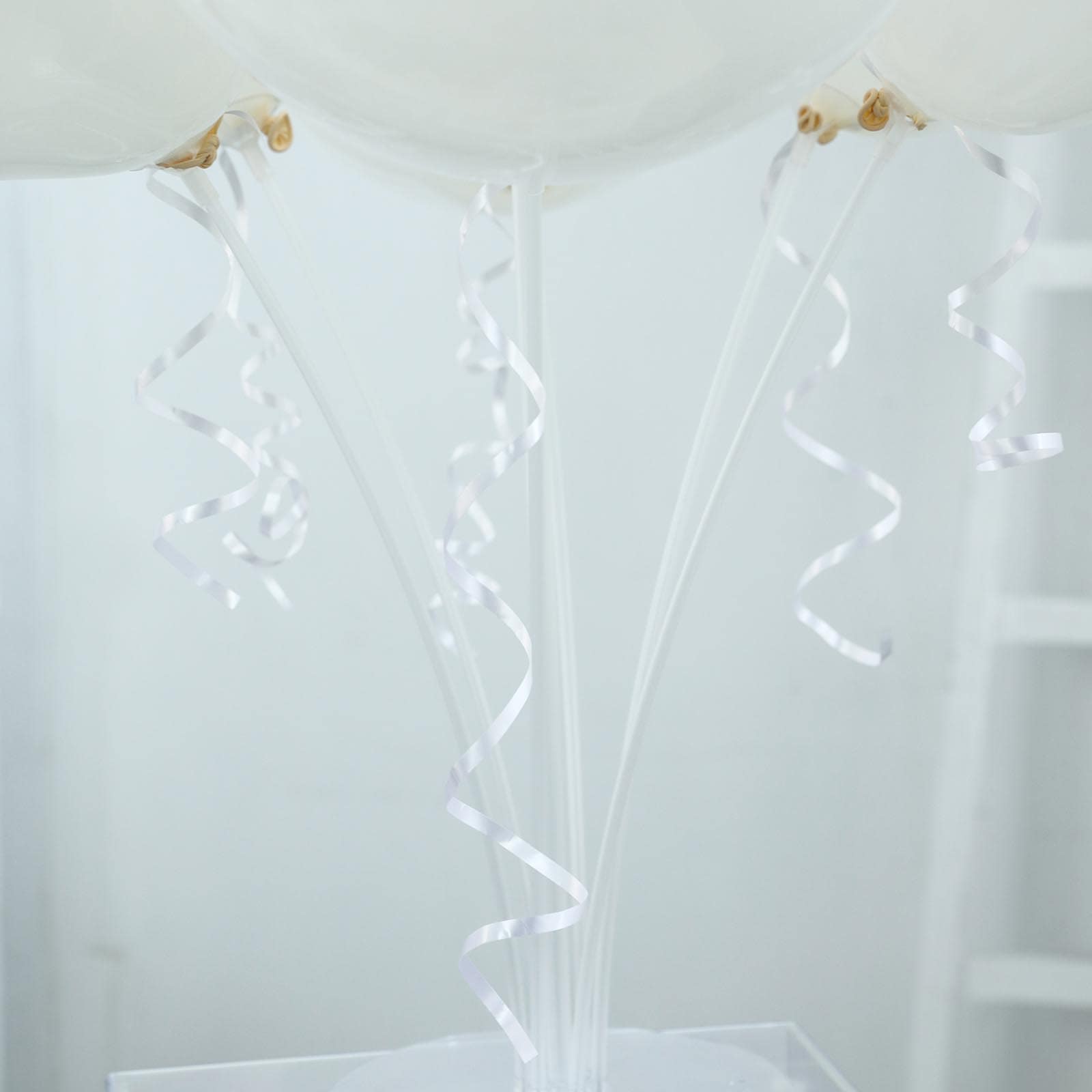 White balloon arch kit with curling ribbons for party decorations.