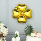 Shiny gold four leaf clover mylar foil balloons on a gray wall.