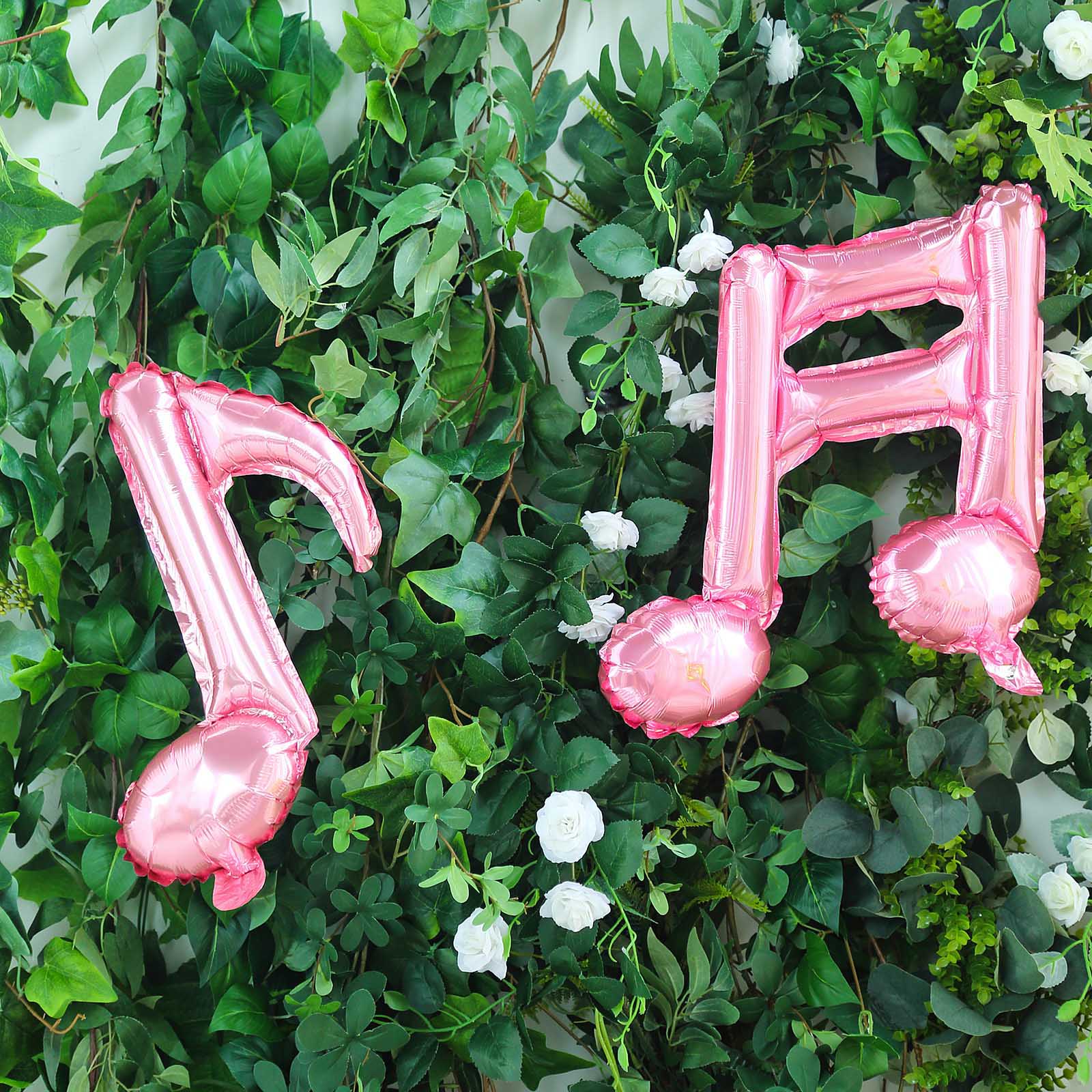 Rose gold music note mylar foil balloons on a greenery background.
