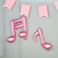 Rose gold music note mylar foil balloons hanging on a wall.