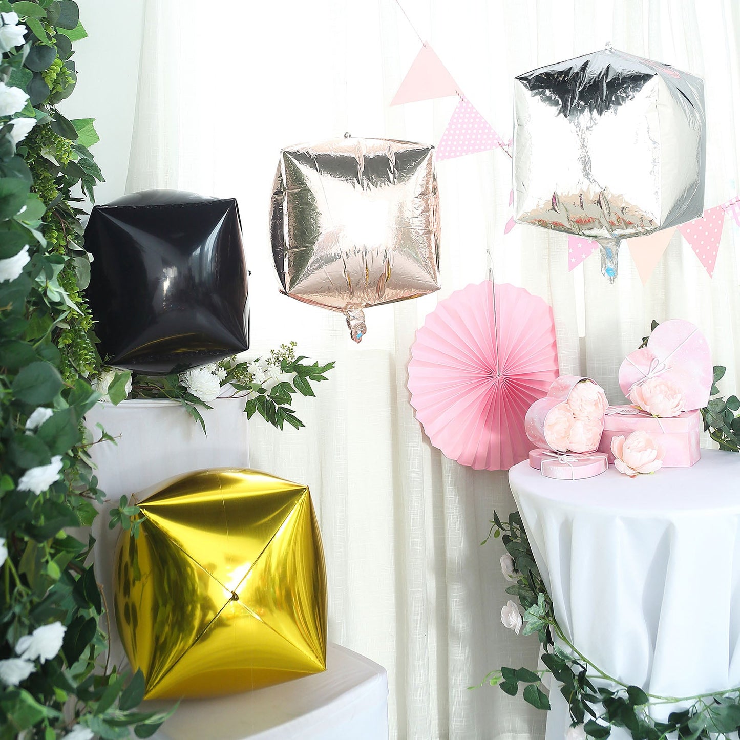 Rose gold cube-shaped mylar balloons in a festive setting.