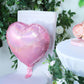 Shiny pink heart-shaped mylar foil balloon on a chair.