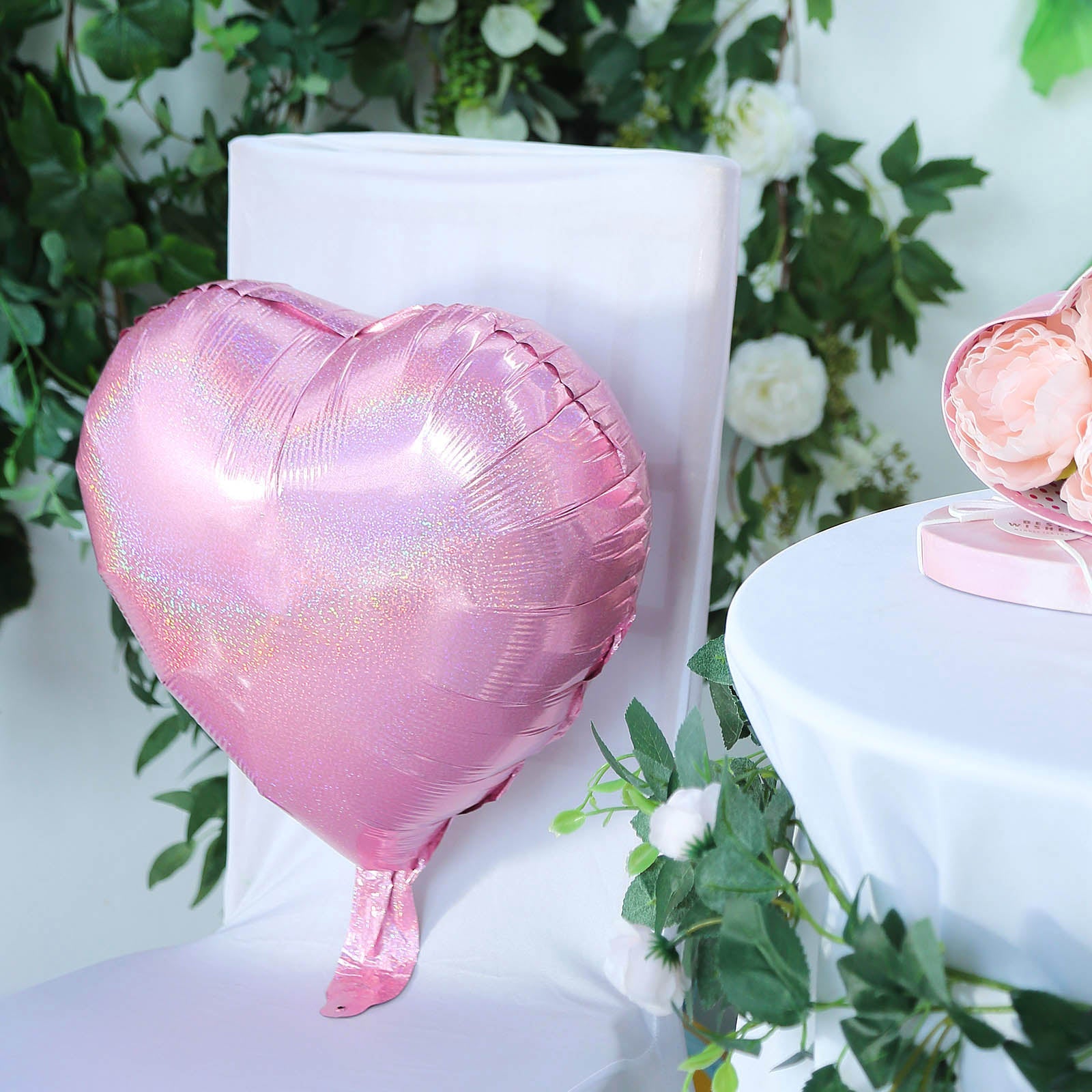 Shiny pink heart-shaped mylar foil balloon on a chair.