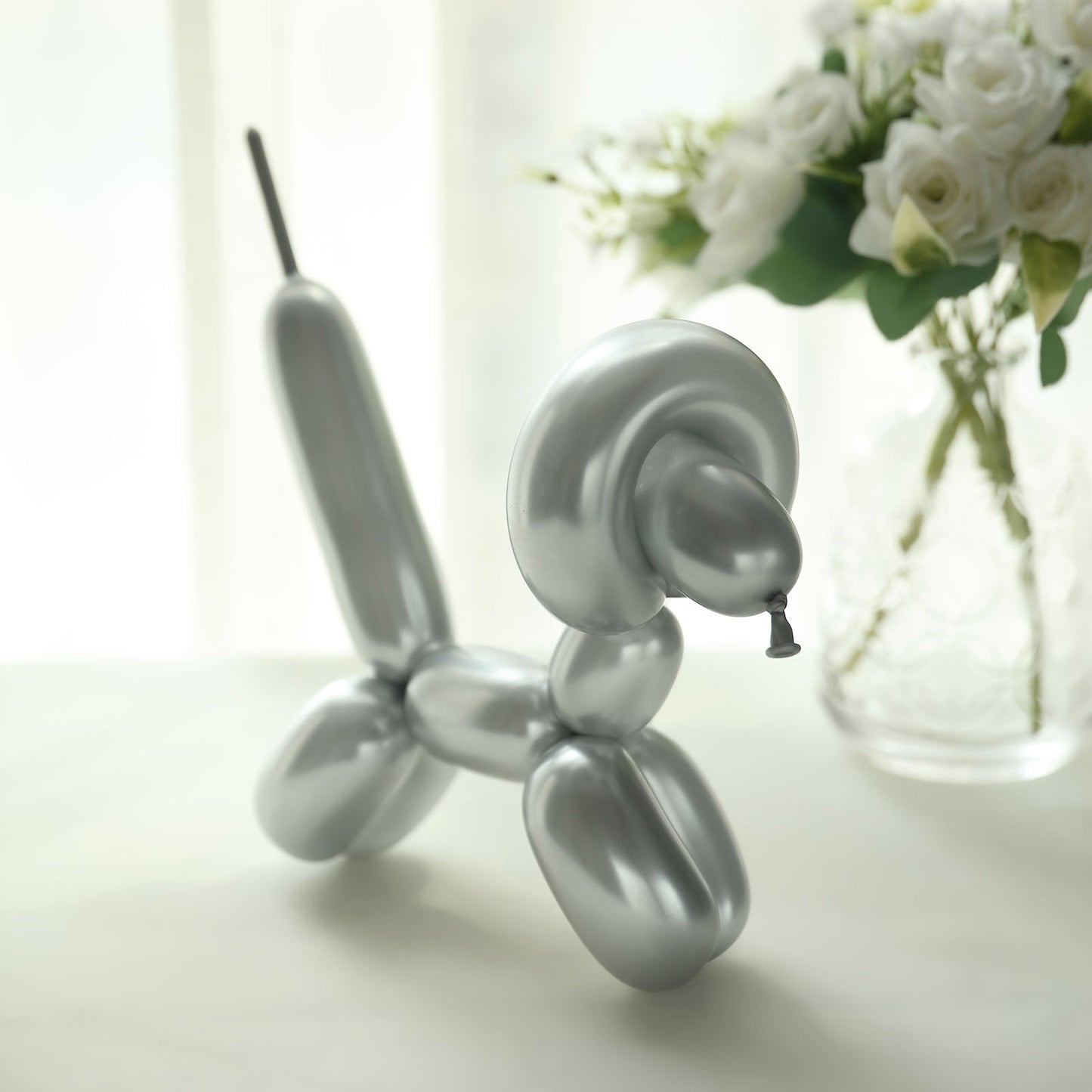 Assorted metallic silver balloon animal sculpture on a table.