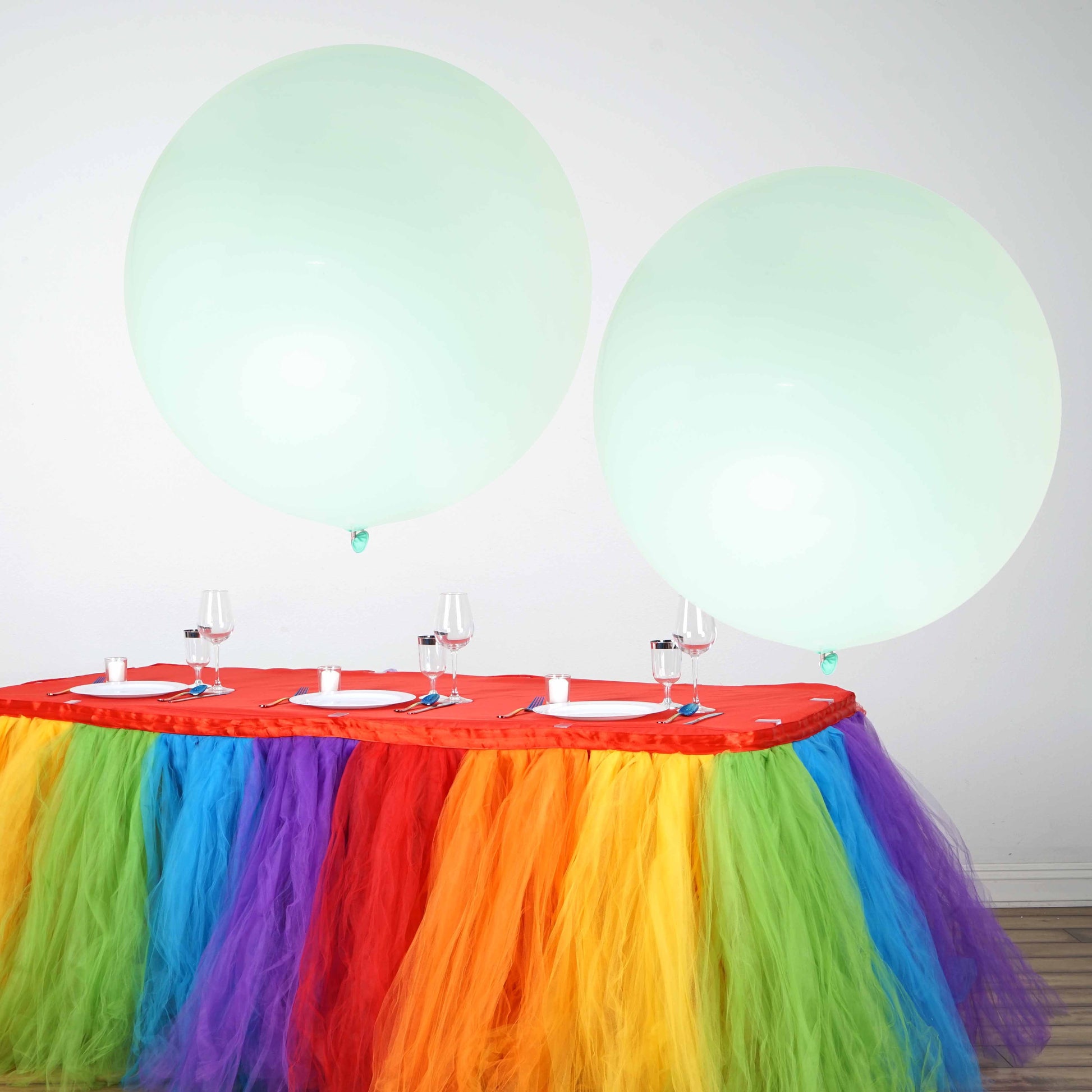 Large matte pastel seafoam balloons on a colorful table setting.